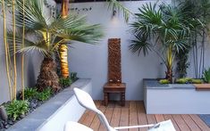 an outdoor patio with wooden flooring and palm trees in the corner, along with white chairs