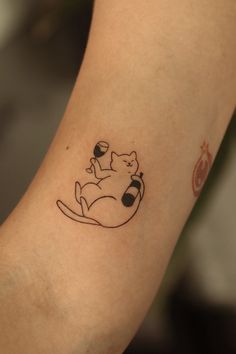 a small tattoo on the arm of a woman with a cat sitting on top of it