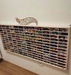 a wall mounted toy storage unit with hot wheels on the top and bottom shelves filled with cars