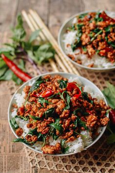 two bowls filled with meat and vegetables next to chopsticks on top of a table