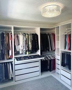 an organized closet with clothes and shoes on the shelves, chandelier hanging from the ceiling