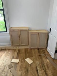 an empty room with wooden floors and unfinished cabinets on the floor next to a door