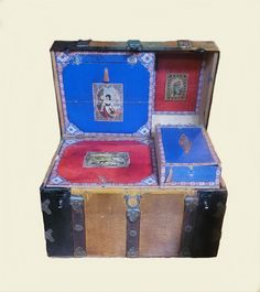 an old trunk with two paintings on the lid and one in it's case