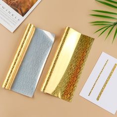 three pieces of paper with gold foil on them next to some cards and envelopes