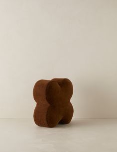 a brown teddy bear sitting on top of a white floor