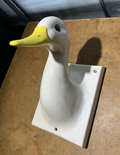 a white duck sitting on top of a wooden table next to a wall mounted light switch