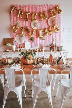 a table set up for a party with gold foil balloons and decorations on the wall