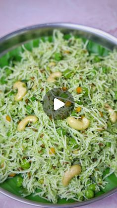 a metal pan filled with green vegetables and nuts on top of a pink table cloth