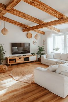 a living room with white furniture and wooden beams on the ceiling, along with a flat screen tv