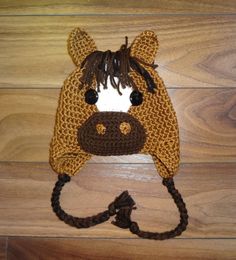 a crocheted hat with a horse's head on it sitting on top of a wooden floor