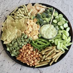 a platter filled with crackers, vegetables and dip