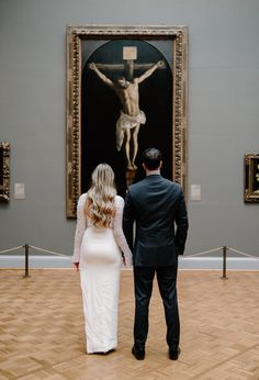 a man and woman standing in front of a painting