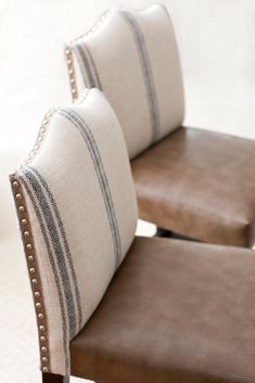 two brown and white pillows sitting on top of a wooden chair next to each other