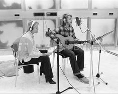 two people sitting in chairs with guitars and microphones on the side of their heads