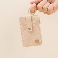 a person is holding a card case with a keychain in their left hand