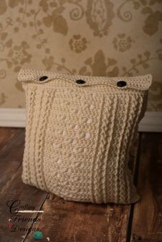 a white knitted pillow sitting on top of a wooden floor next to a wall