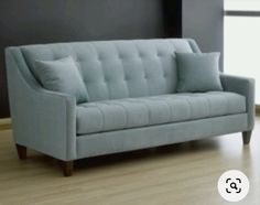 a light blue couch sitting on top of a hard wood floor next to a window