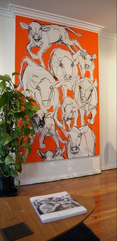 an orange and white painting hangs on the wall next to a potted plant in front of it