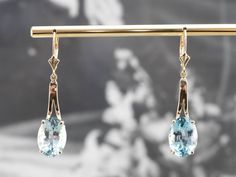 These blue topaz earrings make a real statement! The sparkling blue gems are a beautiful shade of cerulean that can't help but draw the eye. Sleek gold bars create an elegant line and flattering silhouette, perfect for any special occasion! Metal: 14K Yellow Gold Gem: 2 Blue Topaz totaling 14.00 Carats Gem Measurements: 10.0 x 14.0 mm, Oval Earrings Length: 44 mm Earrings Width: 10 mm Marks: "14K (infinity symbol)" Stamped on the Findings Elegant Light Blue Gemstone Earrings, Fine Jewelry Light Blue Earrings For Formal Occasions, Light Blue Fine Jewelry Earrings For Formal Occasions, Formal Light Blue Fine Jewelry Earrings, Formal Topaz Earrings, Classic Blue Topaz Earrings For Wedding, Classic Blue Topaz Wedding Earrings, Elegant Aquamarine Earrings, Elegant Blue Topaz Earrings