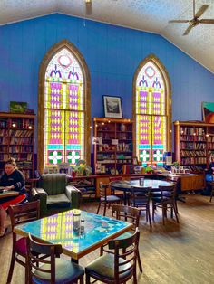 the interior of a library with stained glass windows and people sitting at tables in front of them