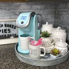 there is a coffee maker and cups on the counter