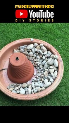 a bowl filled with rocks and a water fountain on top of it in the grass