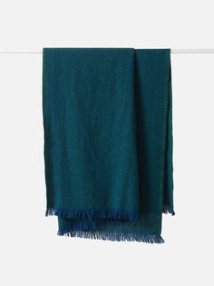 a teal towel hanging on a clothesline with blue fringes around the edge