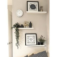 two white shelves with pictures, plants and framed photos on them are against the wall