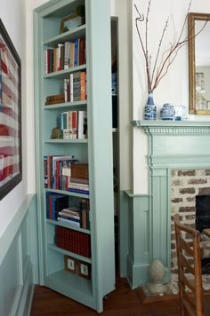 a living room with a fireplace and bookshelf in the corner next to a mirror