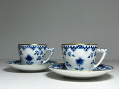 two cups and saucers with blue flowers on them