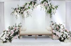 a white bench with flowers and greenery on it