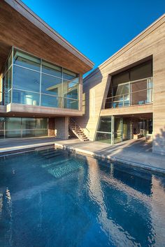 an outdoor swimming pool in front of a modern house