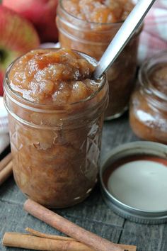 two jars filled with apples and cinnamon on top of a table