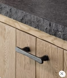 a kitchen counter with black granite top and wooden cabinet doors, showing the handles on each drawer