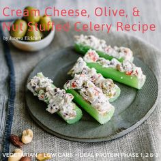 four pieces of celery sitting on top of a plate next to some nuts