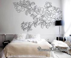 a bed sitting under a large wall decal next to a white chair and lamp