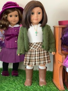 three dolls standing next to each other in front of a wooden table and chair with green grass