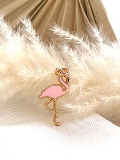 a pink flamingo pin sitting on top of white feathers