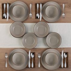 a table set for six with silverware on it and placemats in the middle