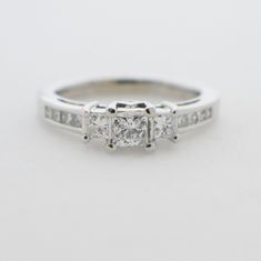 a three stone diamond ring with channel set diamonds on the sides and side stones at the top