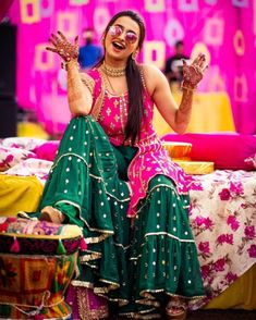 a woman sitting on top of a bed with her hands in the air and smiling