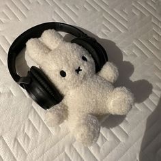 a white teddy bear with headphones on top of a bed in the middle of it