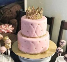 a three tiered cake with a crown on top sits on a table next to macaroons