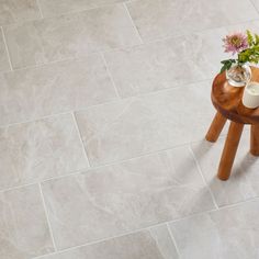 a small wooden table with flowers on it in front of a white tile flooring