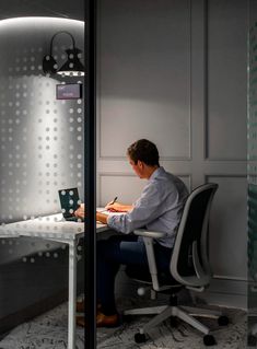 a man sitting at a desk in front of a laptop computer on top of a white table