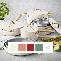 white pots and pans with gold handles on a marble countertop next to a cutting board