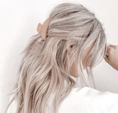 a woman with blonde hair wearing a white shirt and a brown bow in her hair