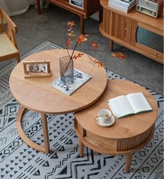 two wooden tables with books and vases on them in a living room area next to other furniture