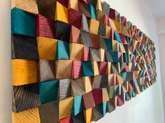 a wall hanging made out of wood with different colors and shapes on the side of it