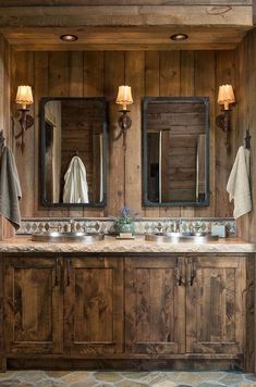 a rustic bathroom with double sinks and wood paneling on the walls, along with two mirrors